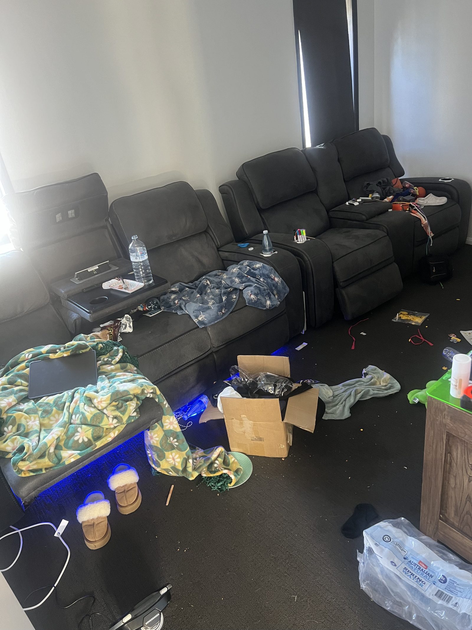 A living room strewn with blankets, boxes and rubbish before a Care for a Clean session